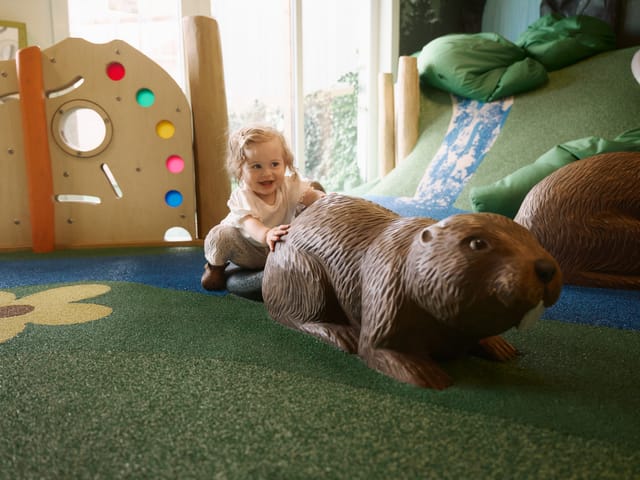 Baby krabbelt in der Indoor-Spielwelt Biberland neben einer Biber-Figur