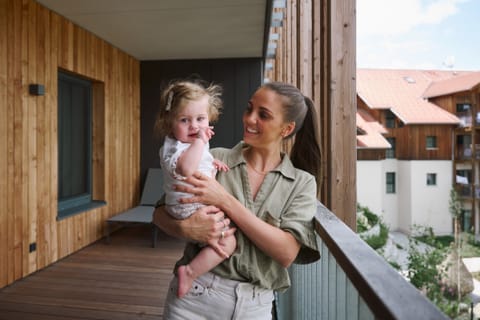 Mama hält ihr lachendes Baby auf dem Balkon der Family-Suite
