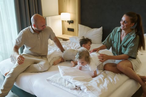 Familie tobt mit zwei Kleinkindern auf dem Bett im Familienzimmer
