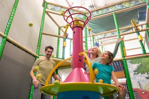 Kinder und Eltern im Indoor-Klettergerüst mit Karussell